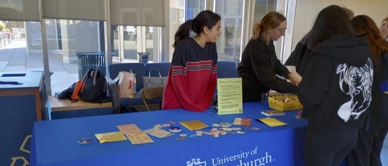 Peer tutors at a table sharing information about the Writing Center with other students.