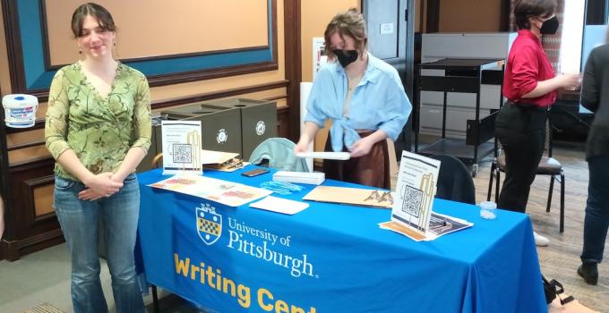 Student standing behind table draped with Writing Center tablecloth handing out information