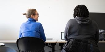 Student and writing center tutor sit side by side at a desk